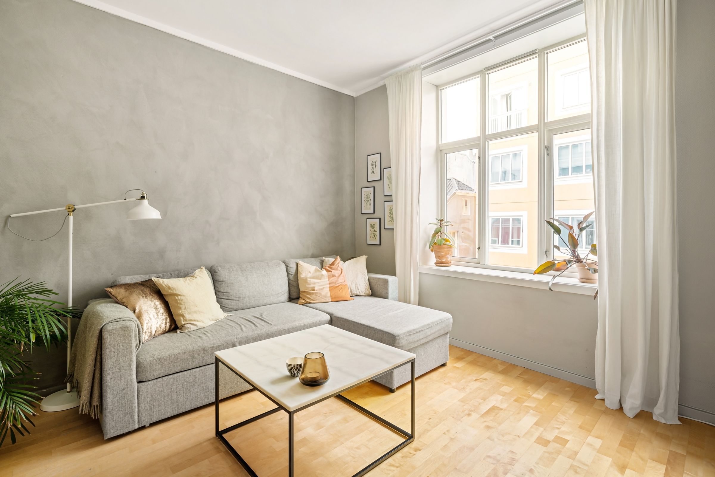 Living room with gray plaster walls, a linen sectional and tall windows onto the street