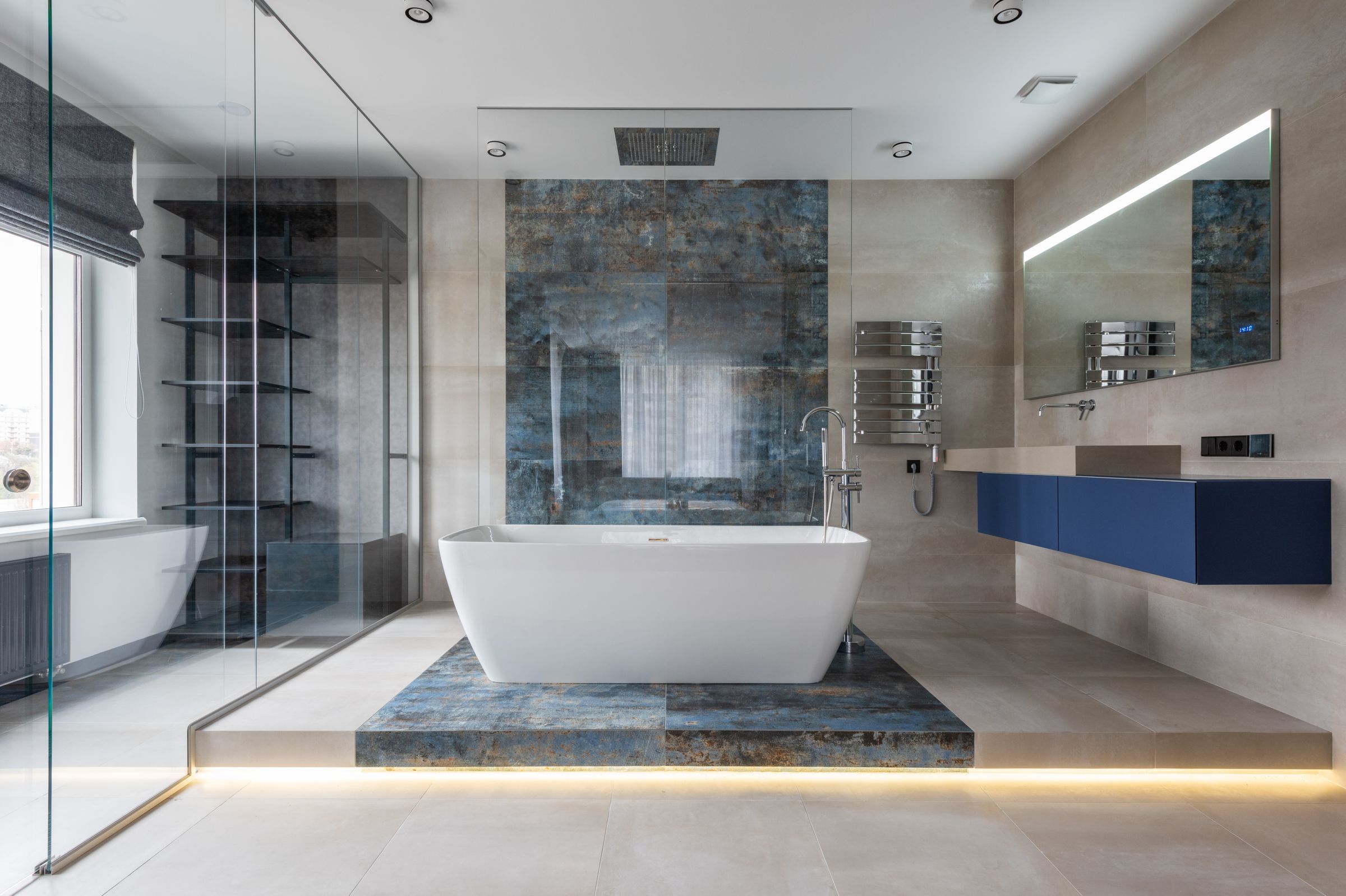 Primary bathroom with a freestanding tub on a blue stone plinth and a lit floating vanity