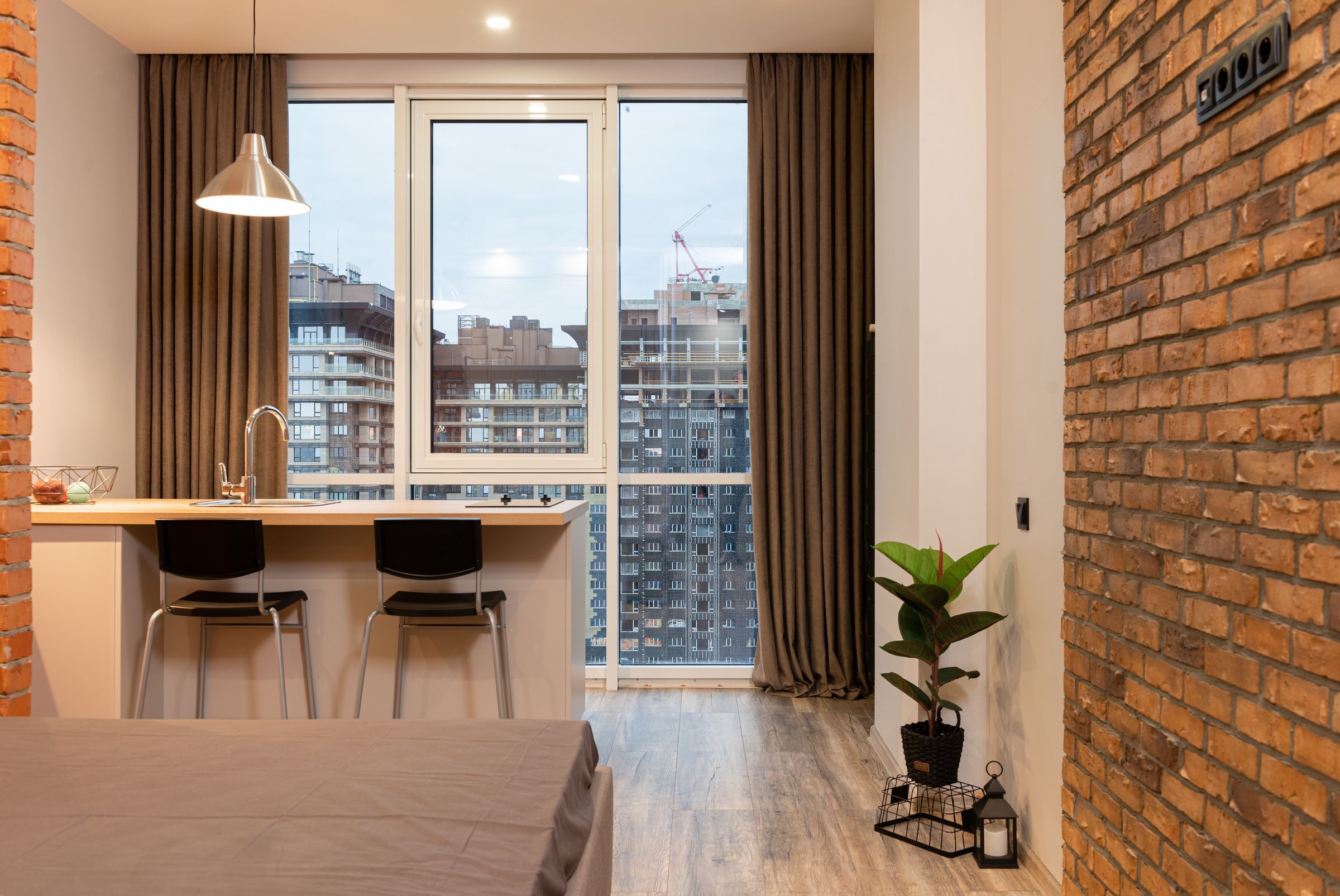 Studio with a kitchen bar at the window, a brick wall and a potted plant