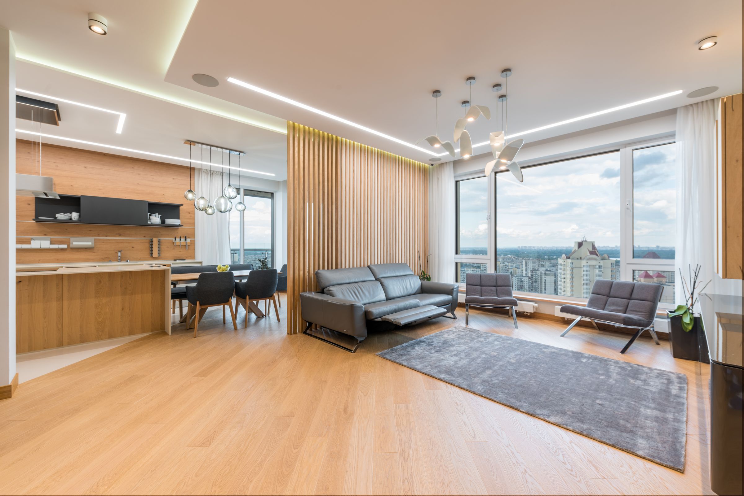 Open living room of a Long Island City penthouse with an oak slat wall and views over Manhattan
