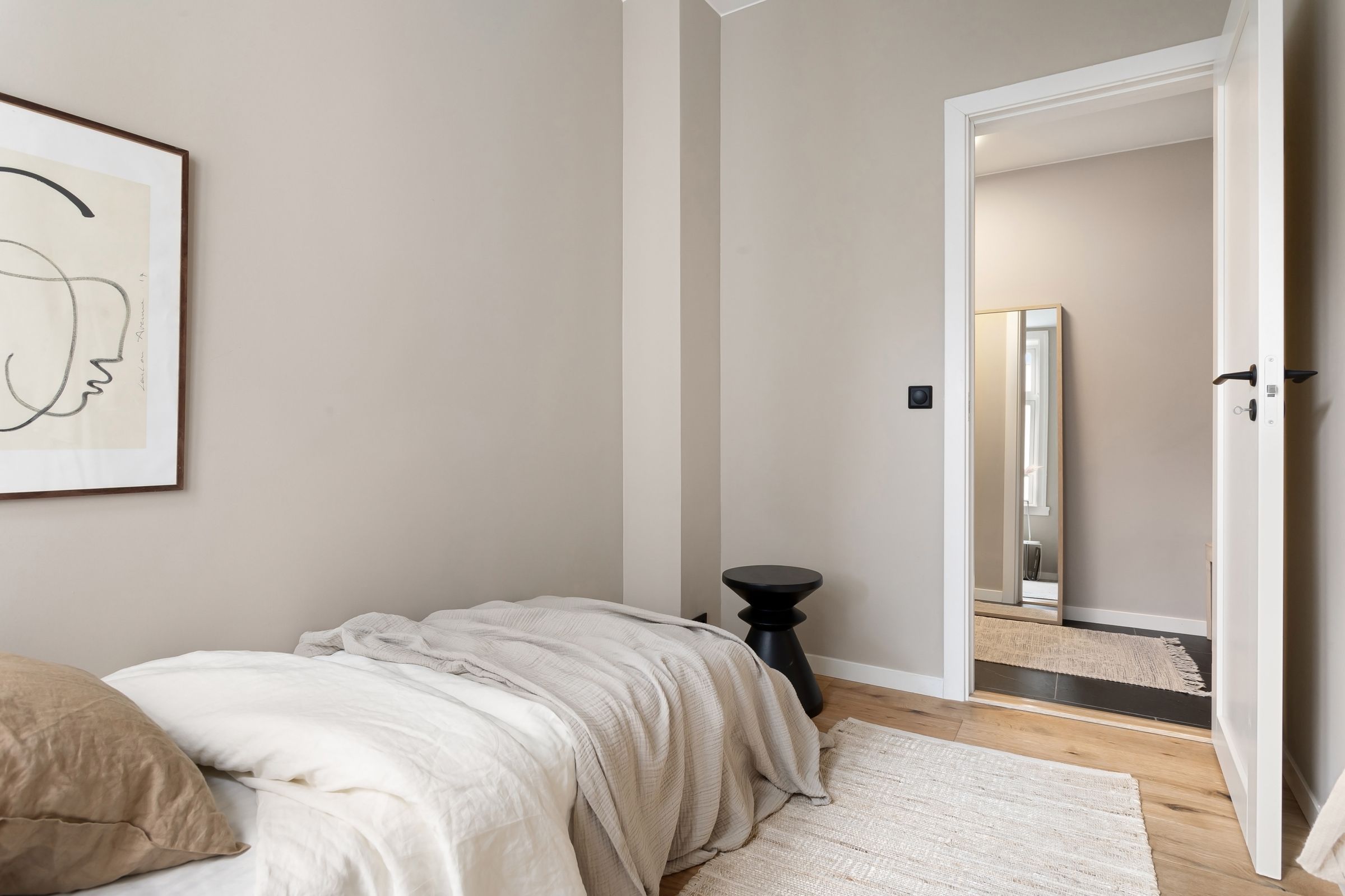 Guest bedroom with a line drawing above the bed and the door to the hallway