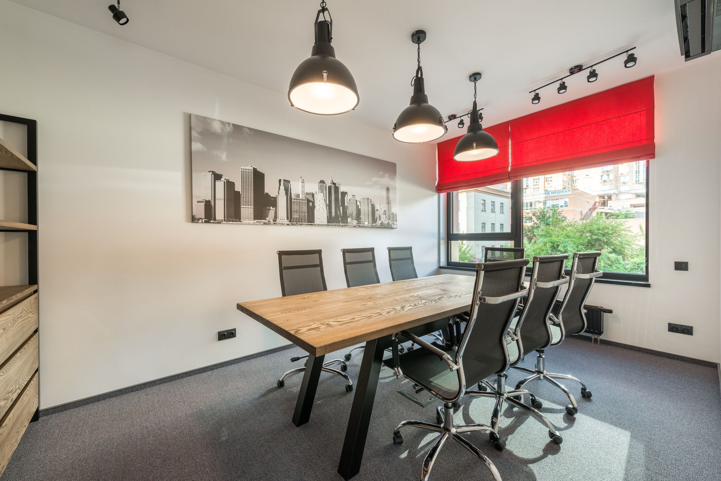Meeting room with a city photograph on the wall and a red blind at the window