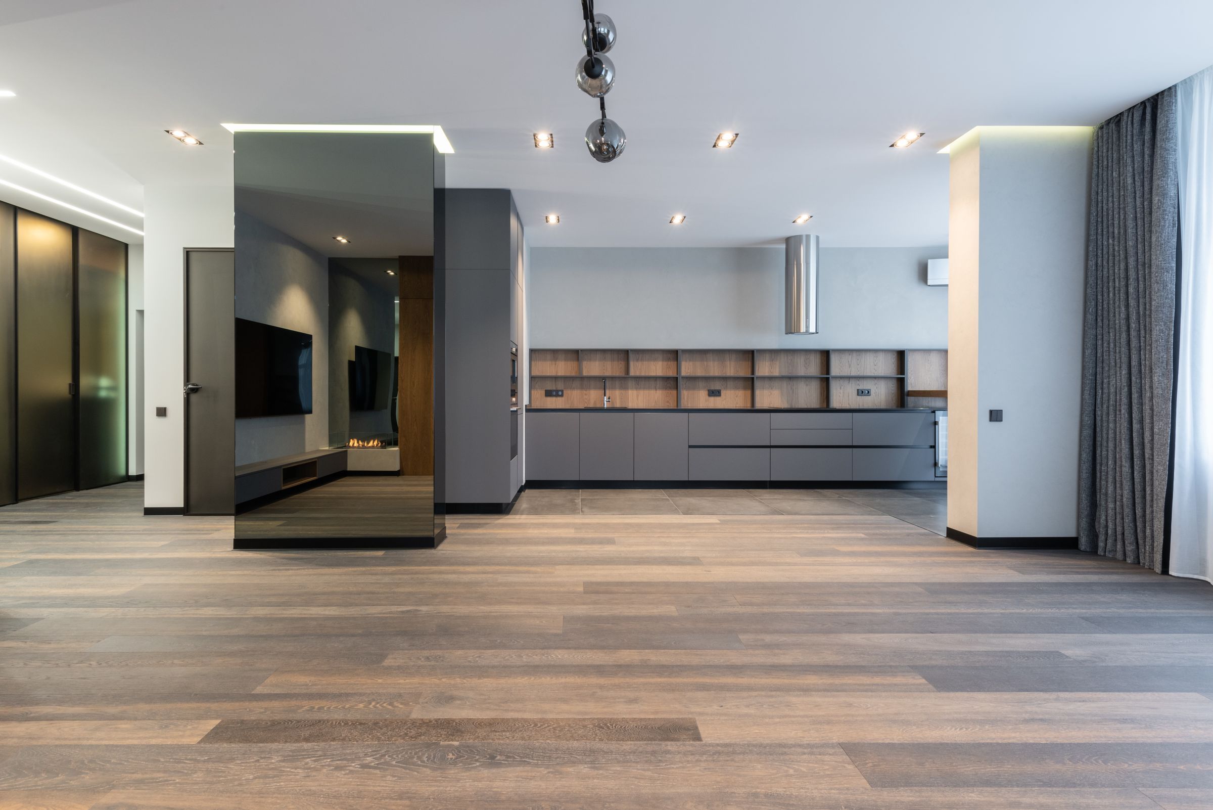 The finished main floor with smoked oak flooring, a mirrored column and the long gray kitchen