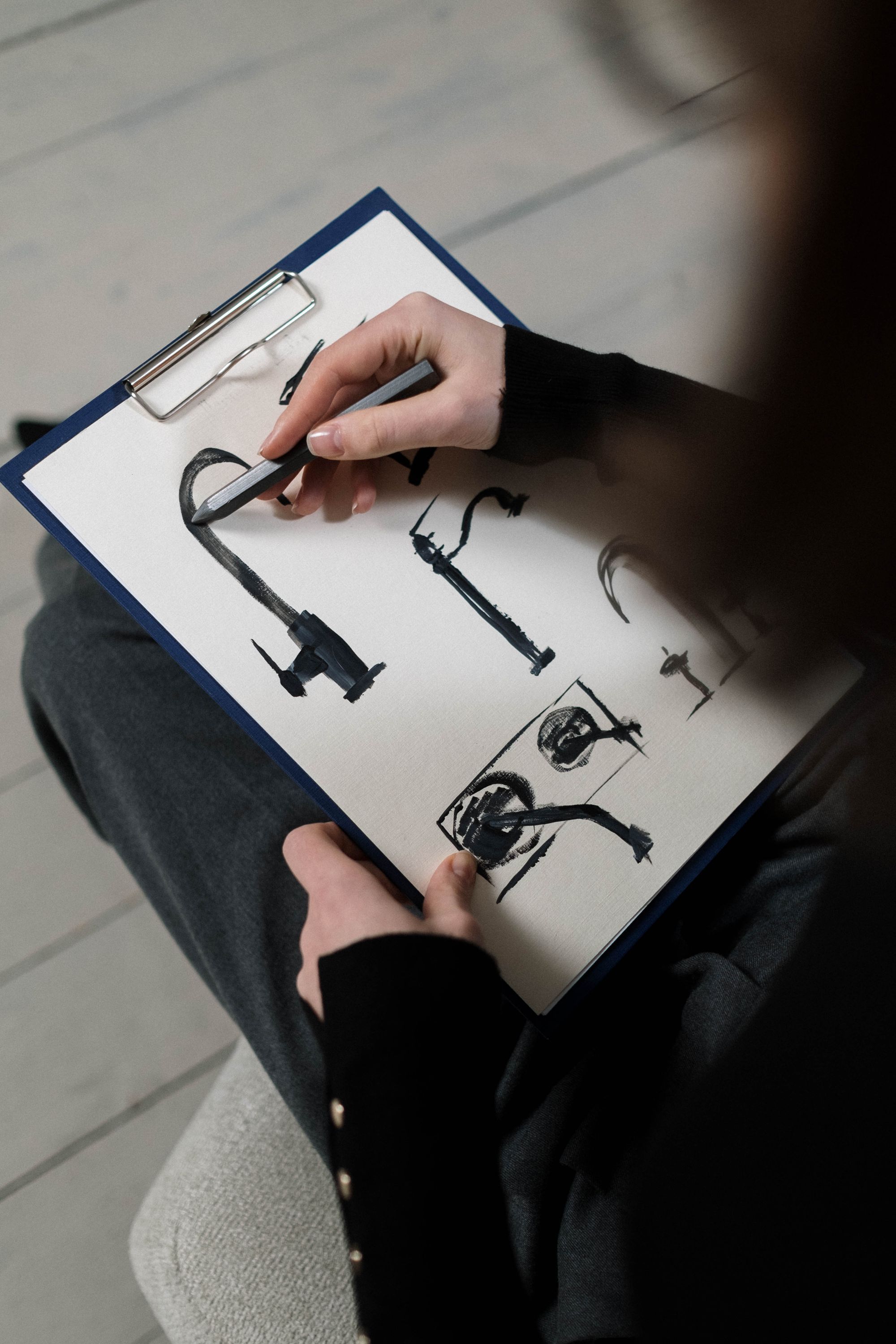 Hand sketching a furniture detail on a clipboard
